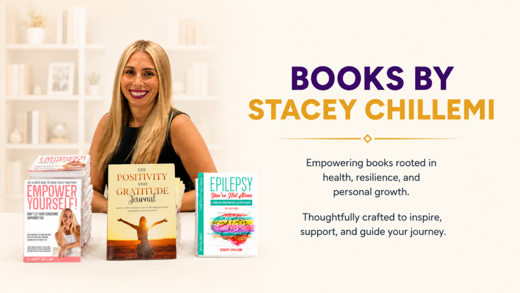 Books By Stacey Chillemi 1 Stacey Chillemi seated behind a display of her books on health, resilience, epilepsy, gratitude, and personal growth.